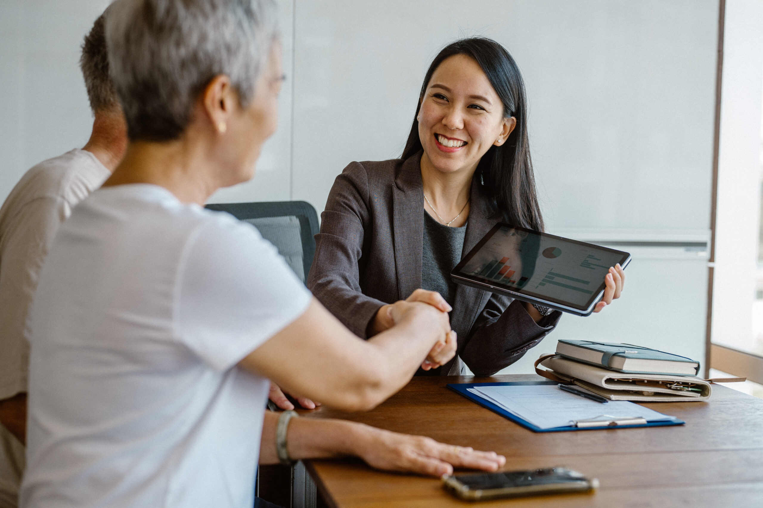 A multiethnic senior couple is signing a business agent agreement with an estate investment consultant during a meeting. - Real estate x Client consultation in Southeast Asia Concept.